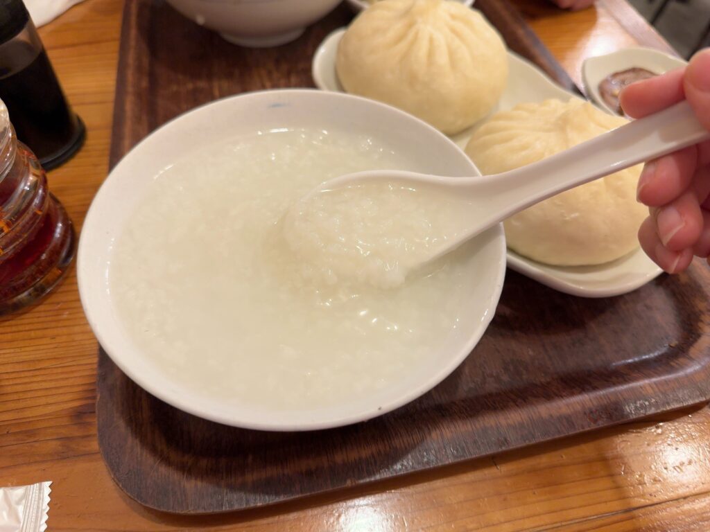 東京 上野御徒町「老酒舗」のおかゆをすくっている写真